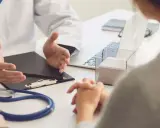 Lekarz omawia z pacjentem diagnozę, być może f43 kod choroby, przy biurku ze stetoskopem i laptopem.