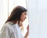 Młoda kobieta zamyślona, oparta o zasłonę. Czy to melancholia co to?