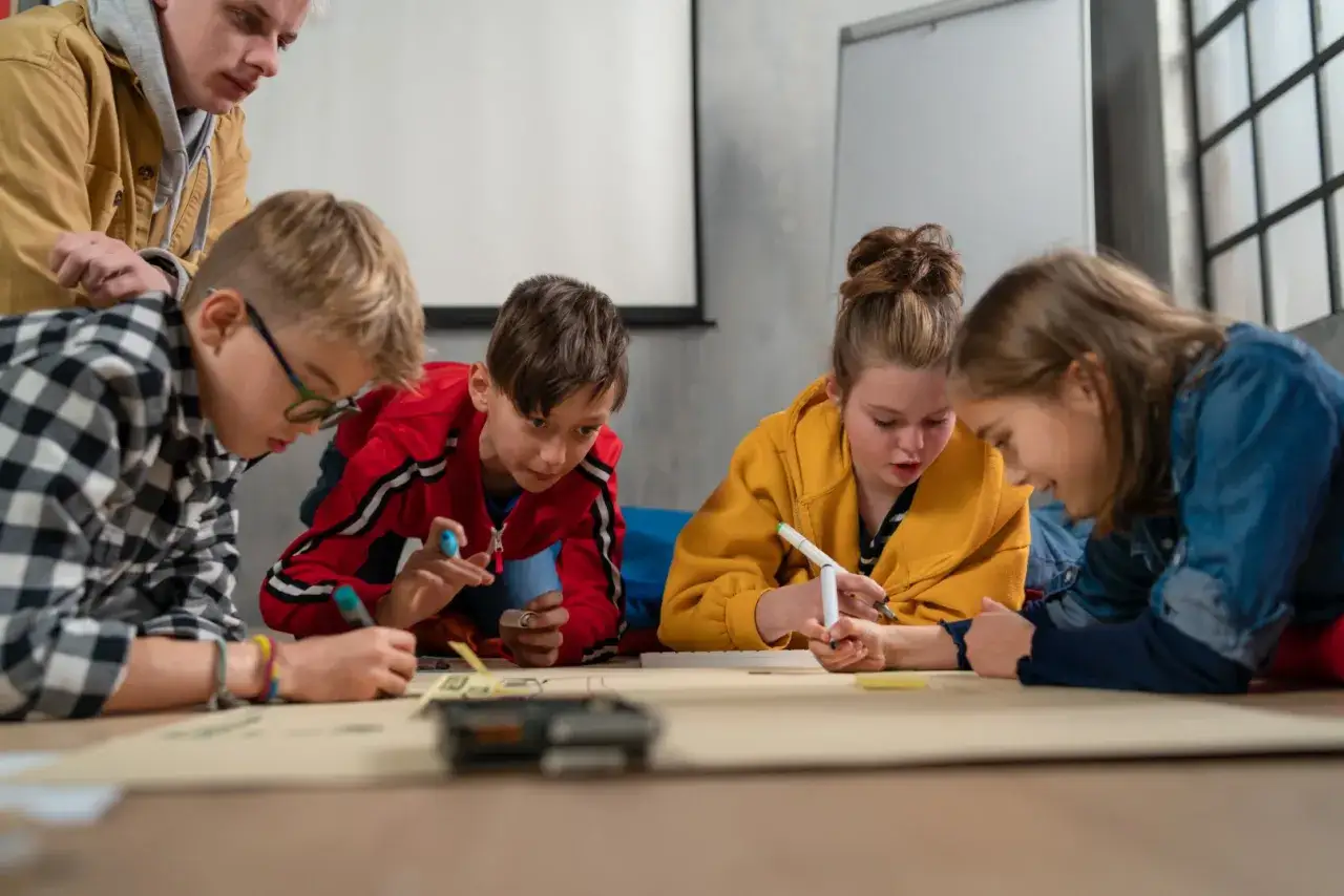 Dzieci i dorosły pracują razem nad projektem, ćwicząc umiejętności społeczne.