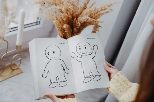 Otwarta książka pokazuje rysunki smutnego i radosnego dziecka, symbolizujące nasze wewnętrzne dziecko.